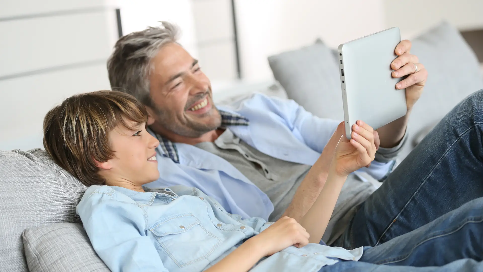 Padre e hijo disfrutando del internet inalambtrico en el sofá