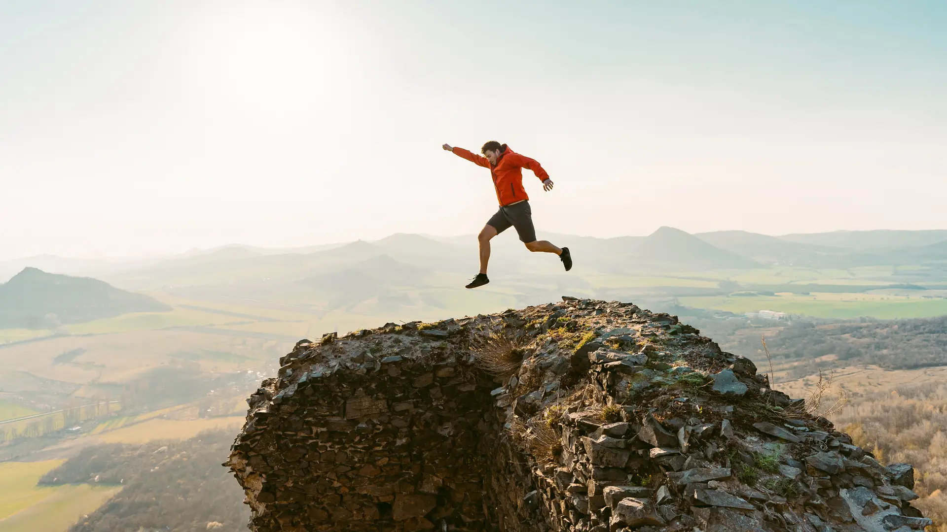 Un hombre saltando en una montaña que representa la portabilidad de Movil Exito