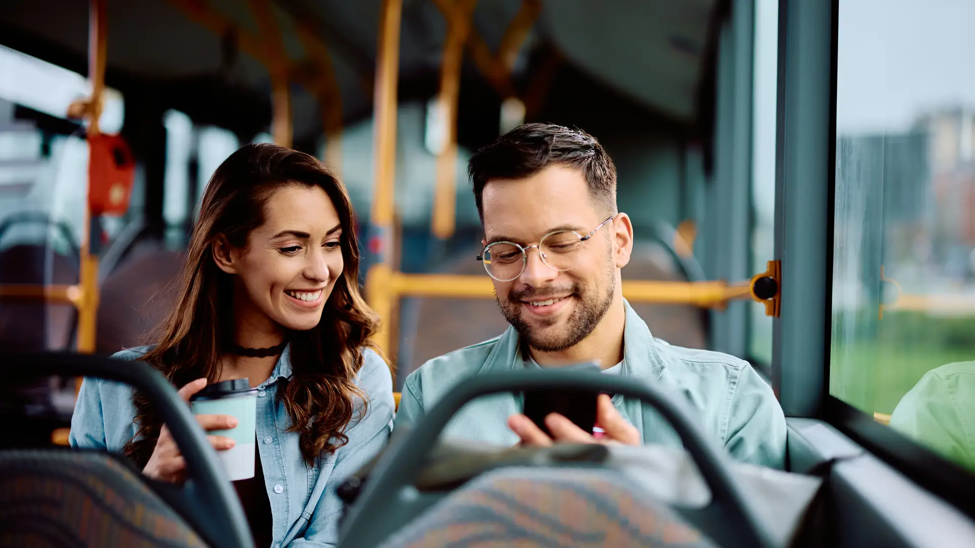 Una pareja en el autobus buscando en su celular tarifas de movil pospago de Movistar