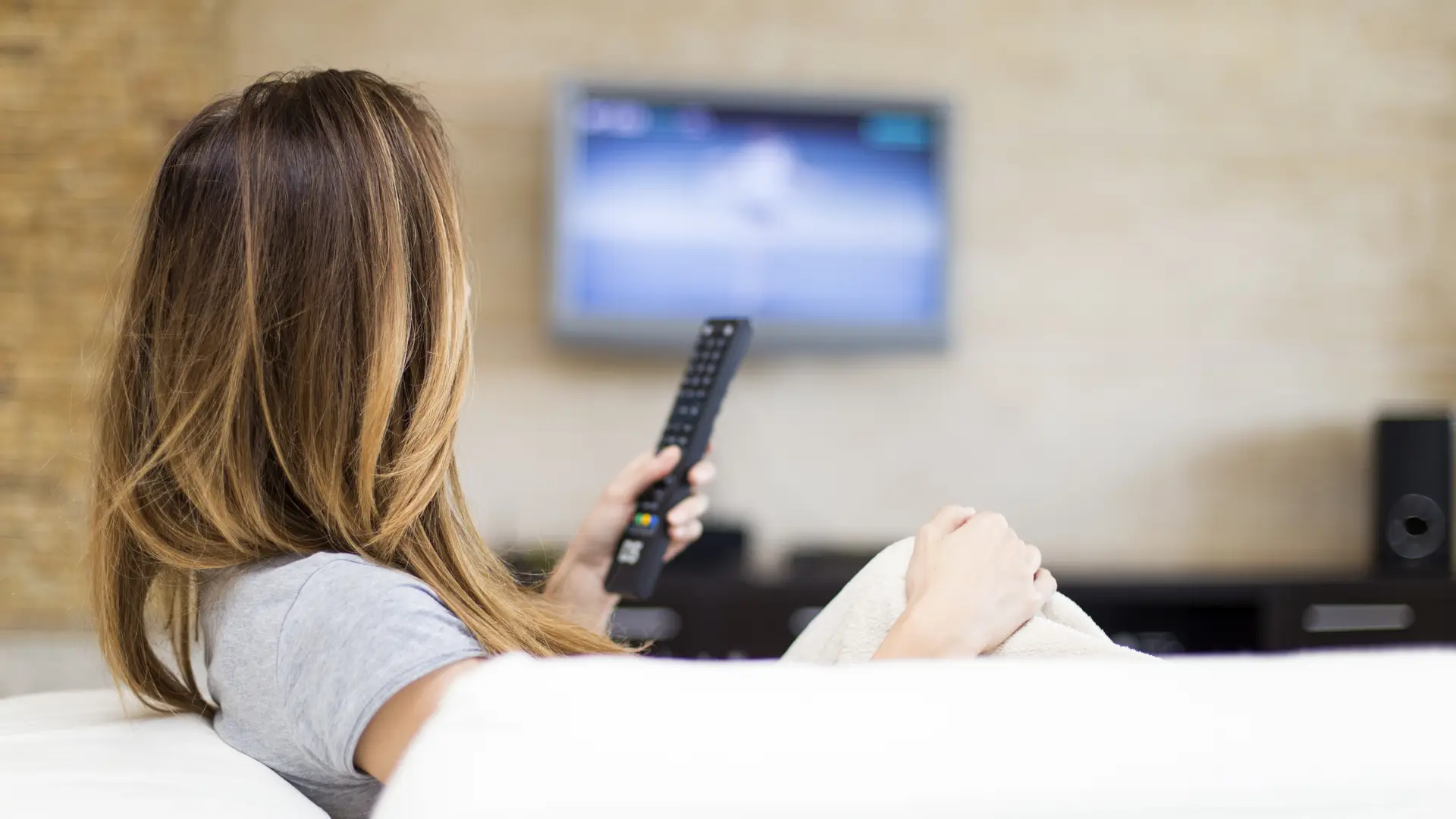 Una mujer viendo la TV gracias a uno de los planes de television de Tigo